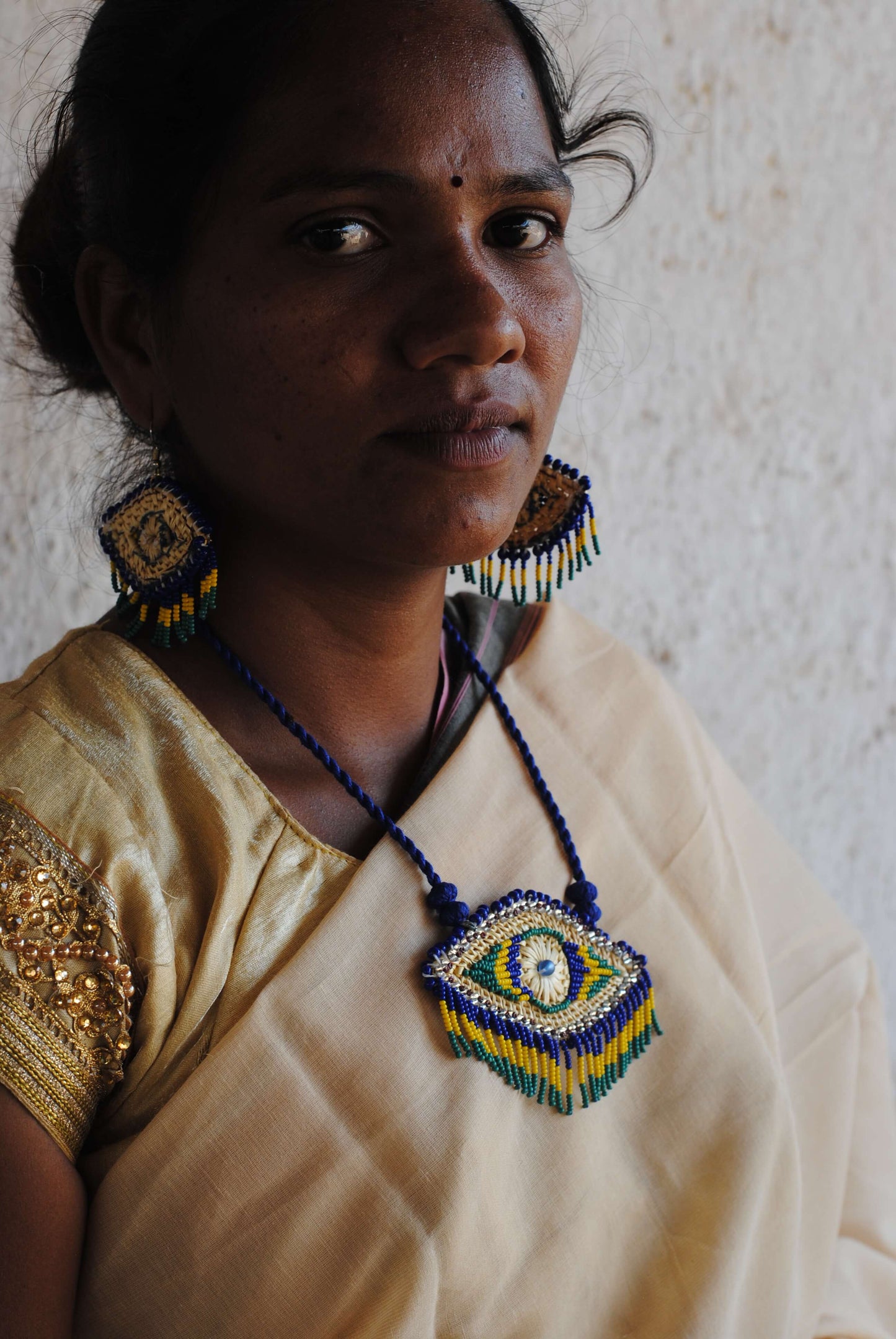 Truna natural fibre golden grass and zardosi handcrafted jewelry from Odisha, nazar blue pendant and earrings set