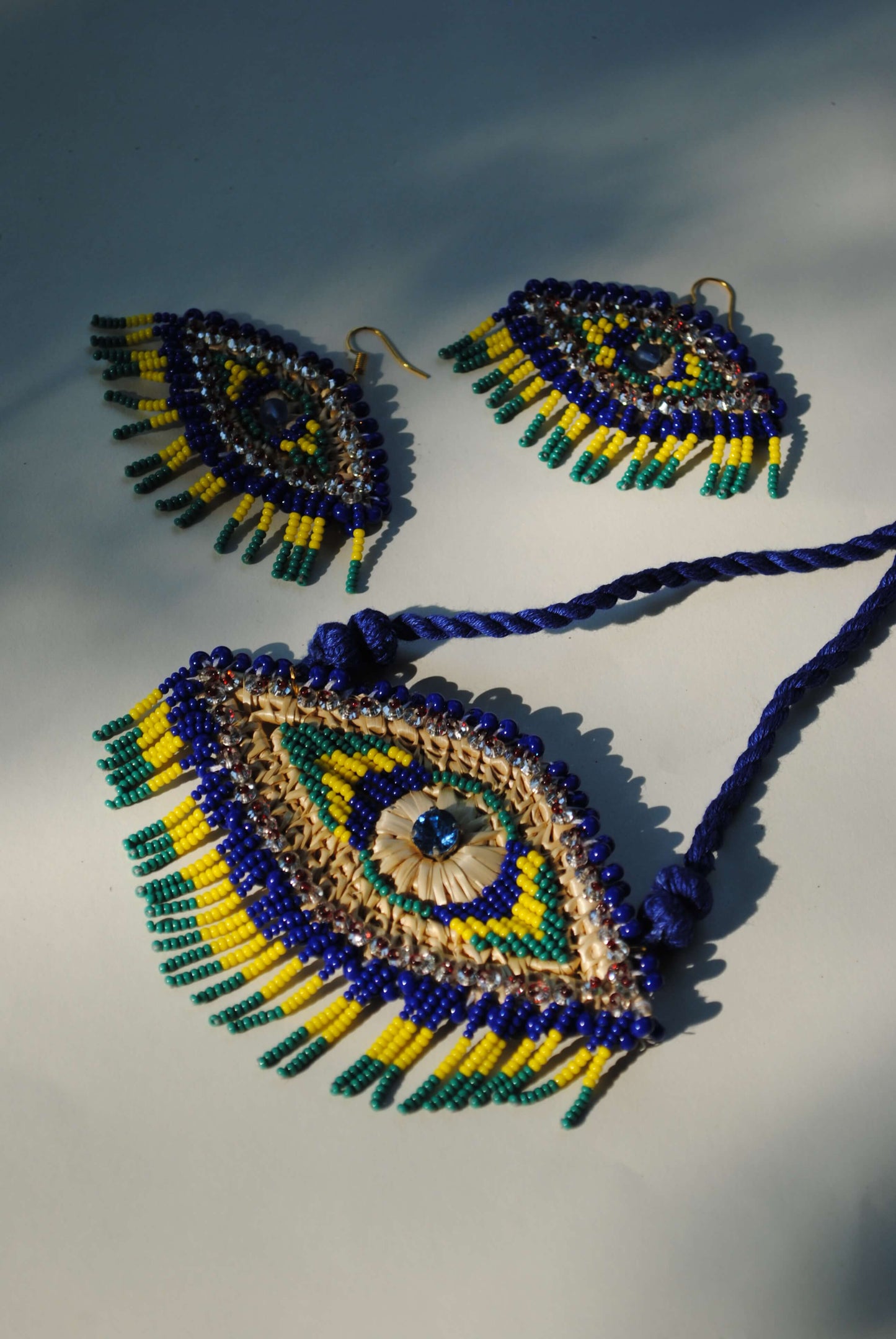 Truna natural fibre golden grass and zardosi handcrafted jewelry from Odisha, nazar blue pendant and earrings set