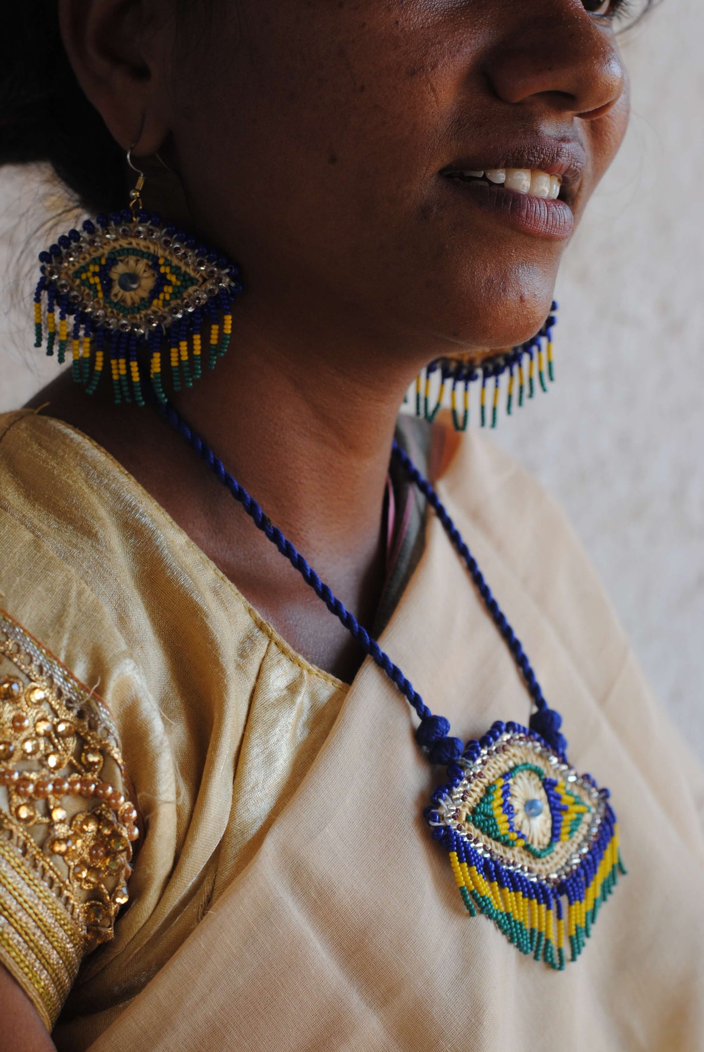 Truna natural fibre golden grass and zardosi handcrafted jewelry from Odisha, nazar blue pendant and earrings set
