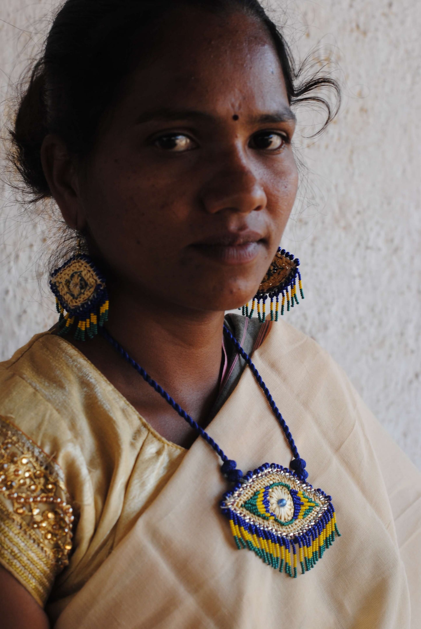 Truna natural fibre golden grass and zardosi handcrafted jewelry from Odisha, nazar blue pendant and earrings set