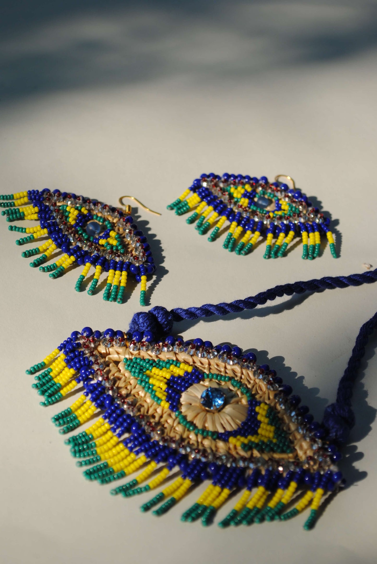 Truna natural fibre golden grass and zardosi handcrafted jewelry from Odisha, nazar blue pendant and earrings set
