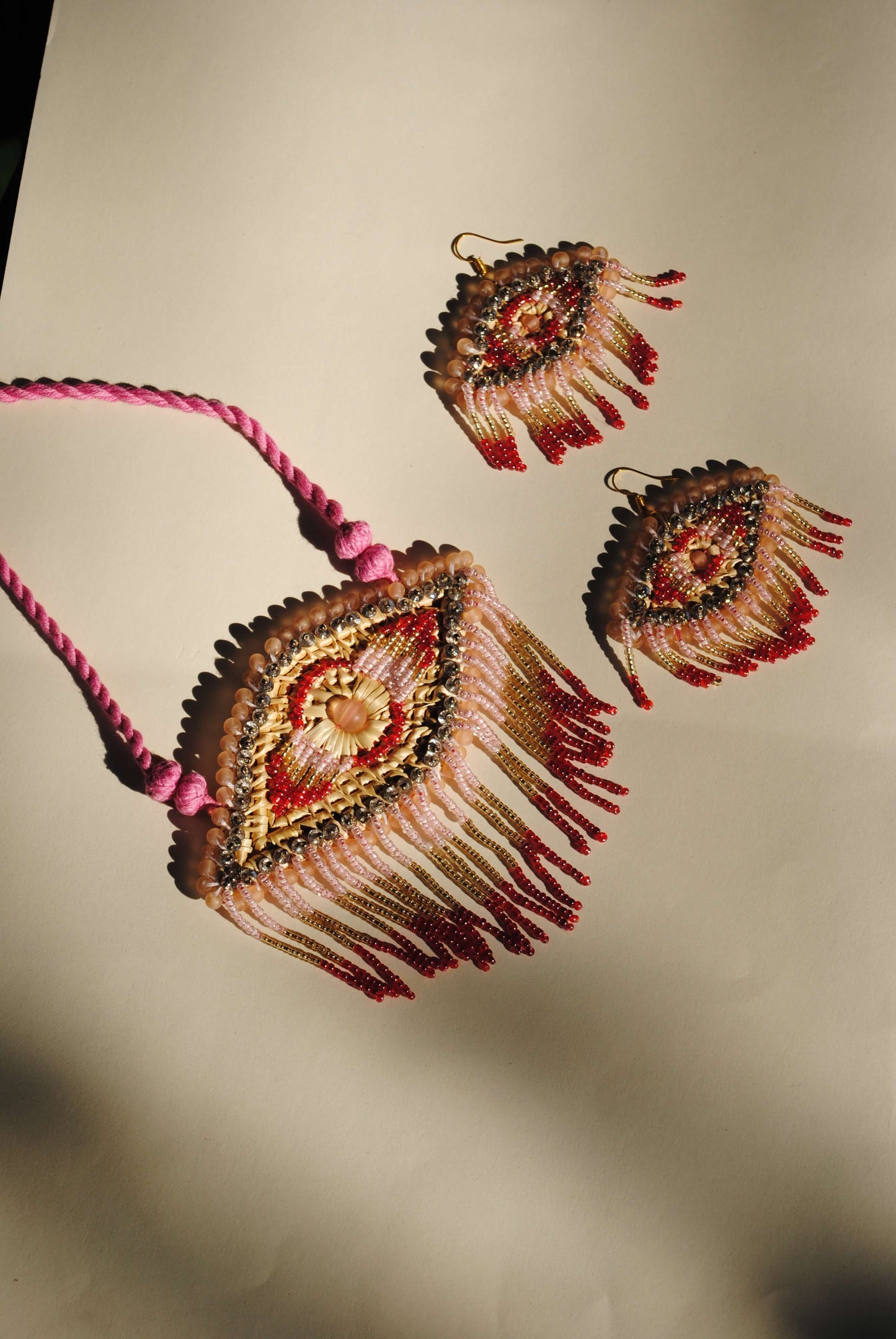 Truna natural fibre golden grass and zardosi handcrafted jewelry from Odisha, nazar pink pendant and earrings set