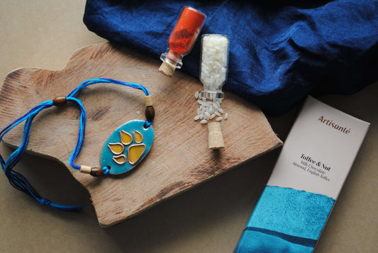 Handcrafted copper enameled rakhi with funky cat pawprints, with a chocolate gift hamper for your furry sibling