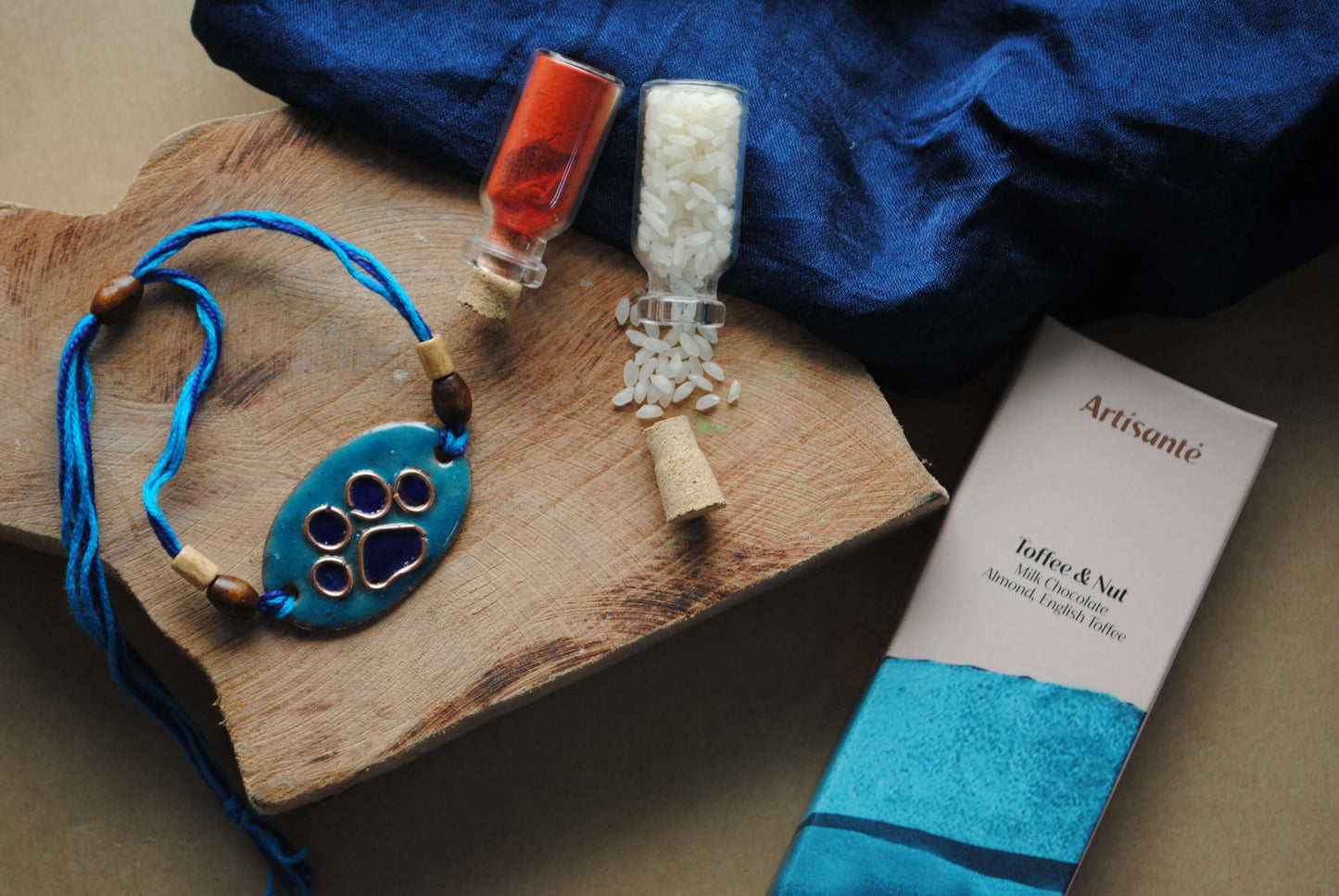 Handcrafted copper enameled rakhi with funky pawprints, with a chocolate gift hamper for your furry sibling