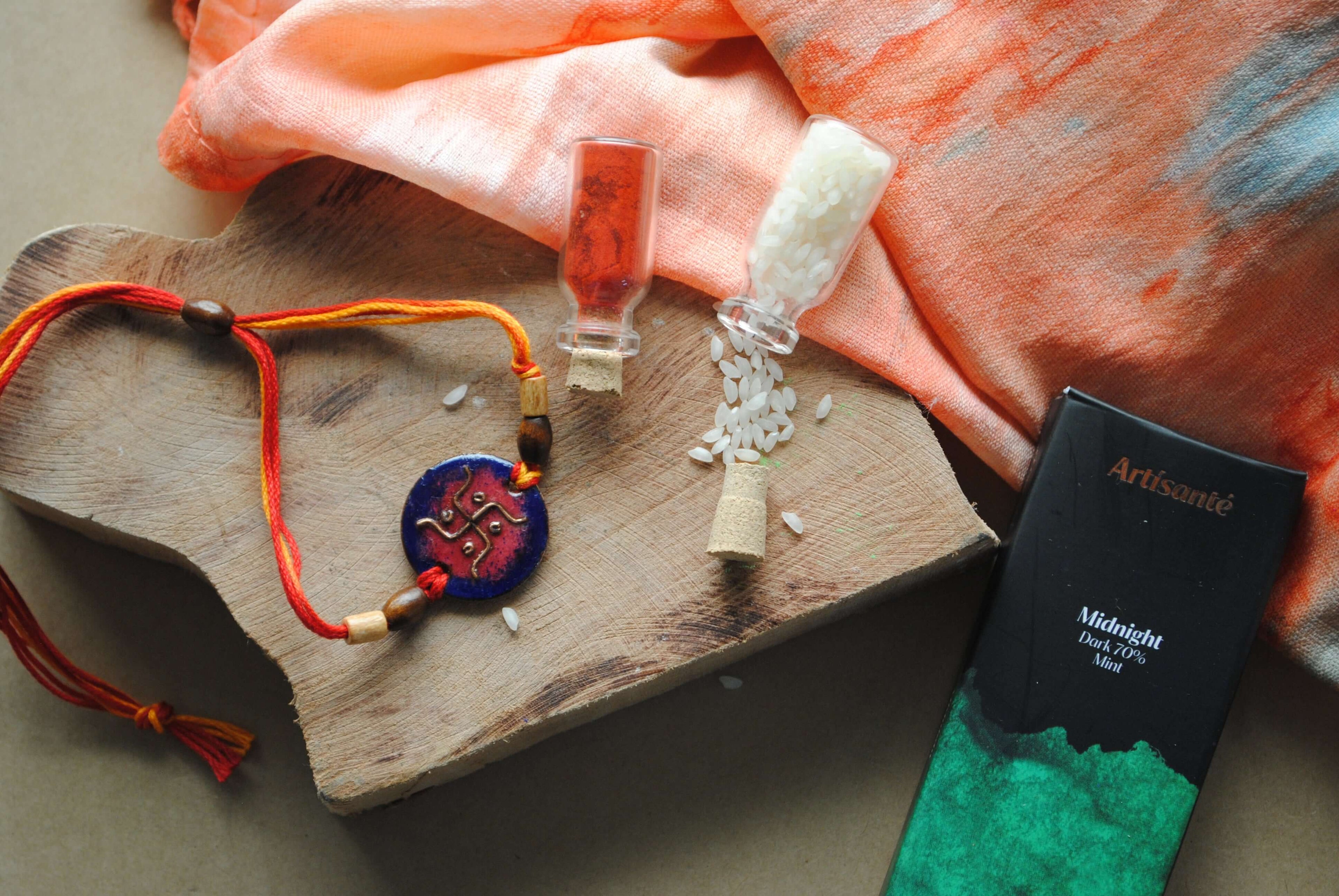 Handcrafted copper enameled rakhi with swastika motifs, string threads. Part of chocolate gift hamper 