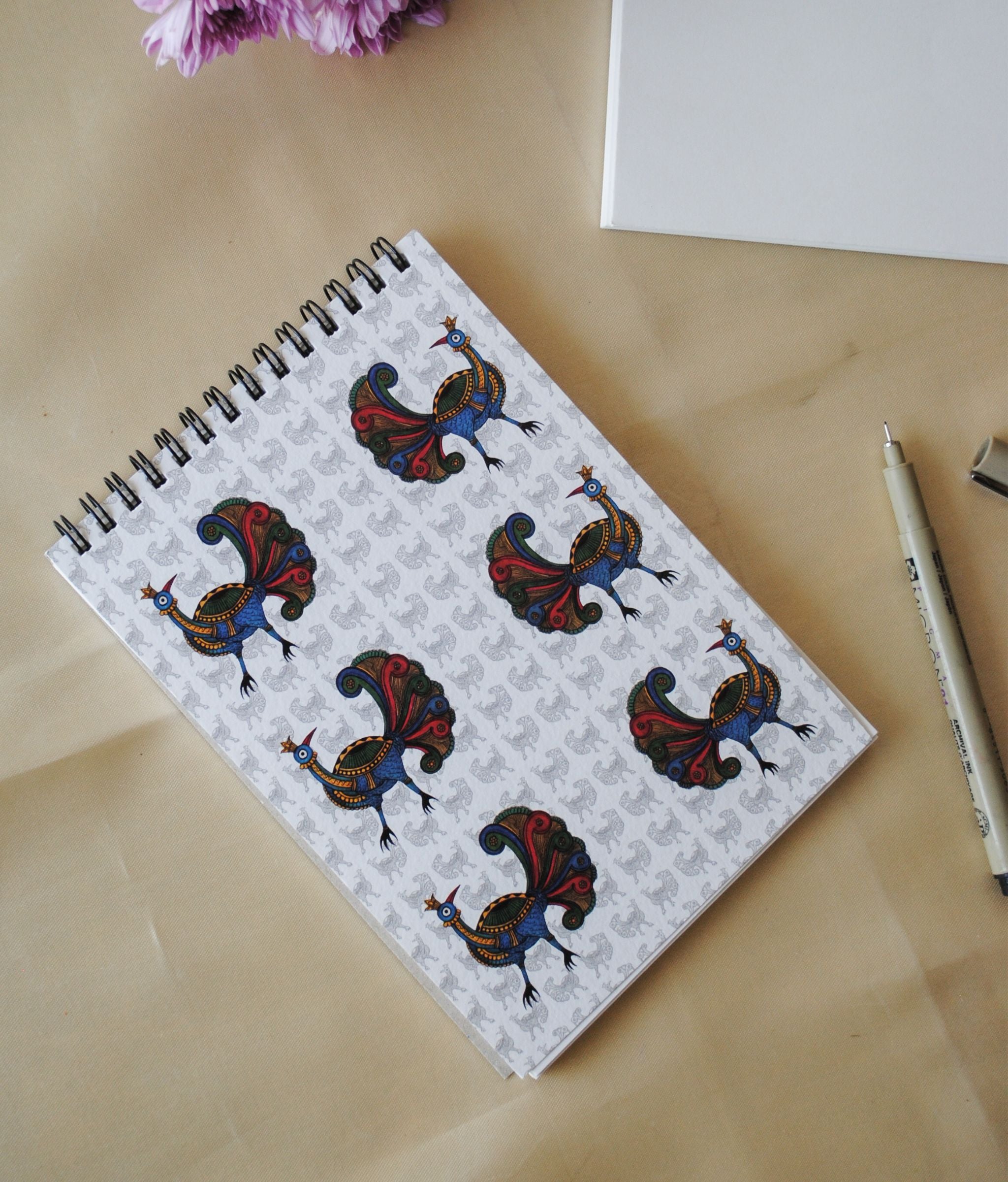 Artwork by native craftsmen of Chitrakathi, Gond, that are used as motifs to create stationery. This one is the peacock motif