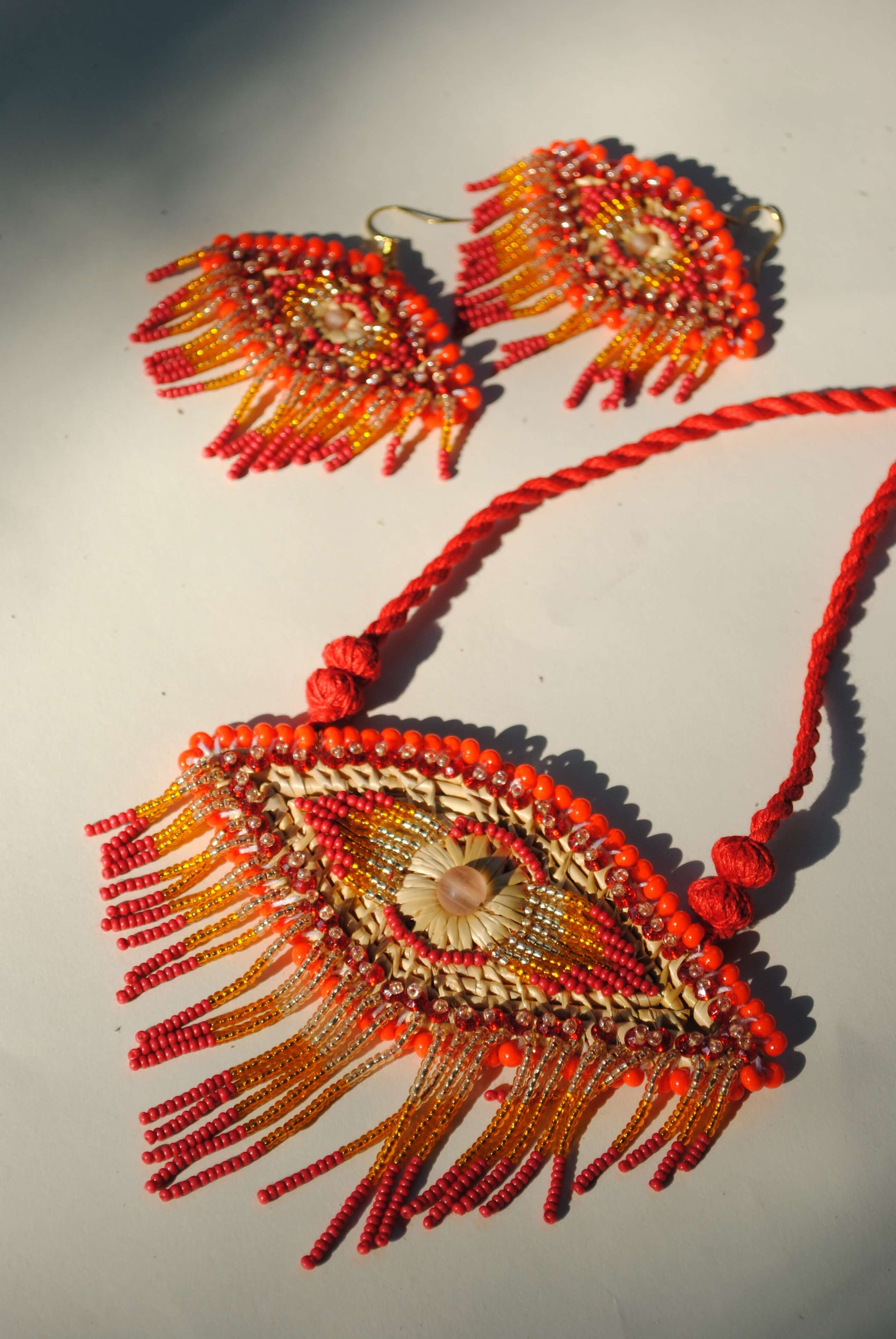 Truna natural fibre golden grass and zardosi handcrafted jewelry from Odisha, nazar red pendant and earrings set