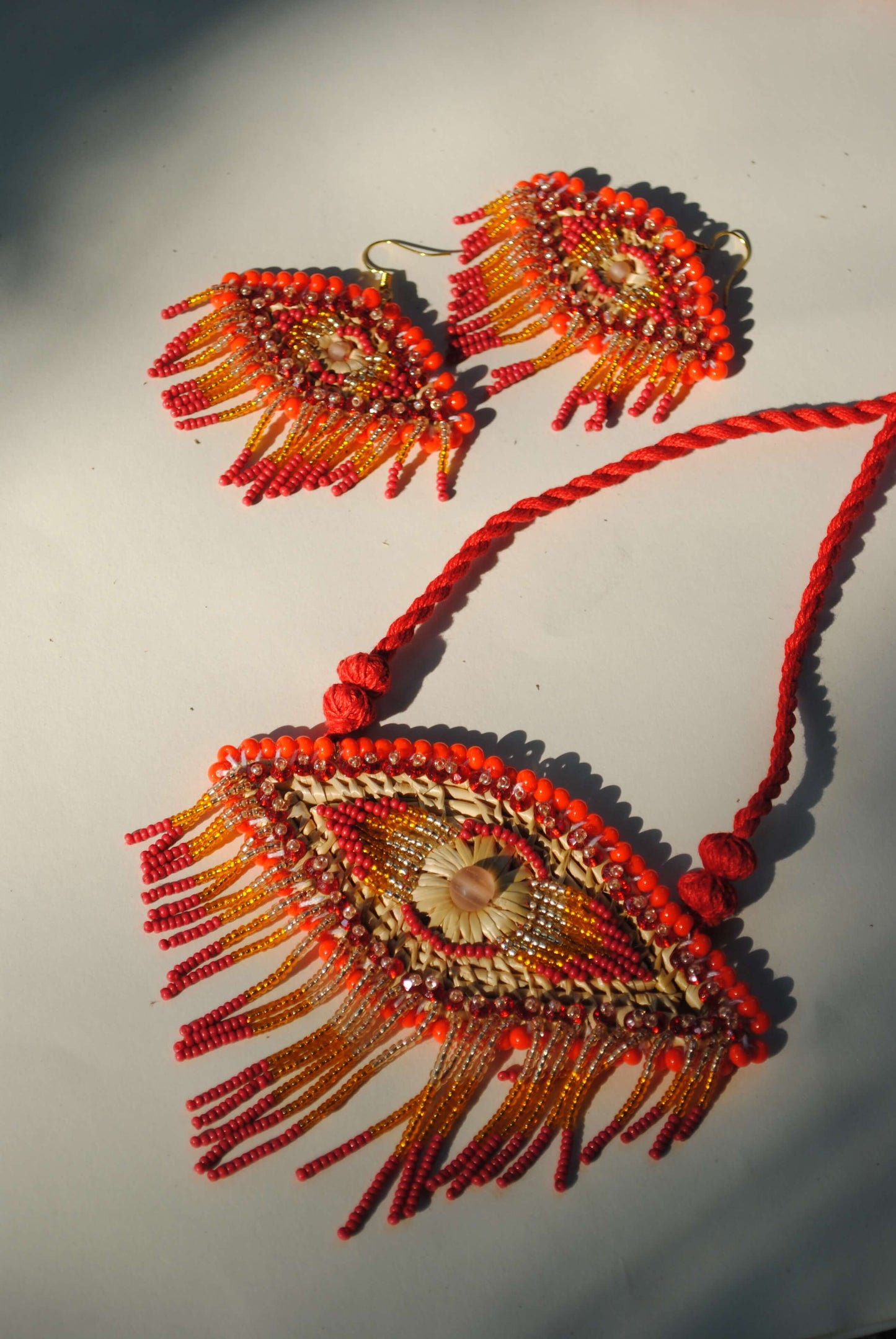 Truna natural fibre golden grass and zardosi handcrafted jewelry from Odisha, nazar red pendant